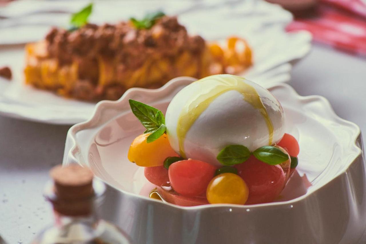 Five Jumeirah Village Dubai Ngoại thất bức ảnh The photo showcases a beautifully presented dish featuring a large ball of fresh mozzarella cheese, sitting atop a colorful assortment of small tomatoes. The tomatoes are a mix of red and yellow, creating a vibrant visual contrast. Fresh basil leaves